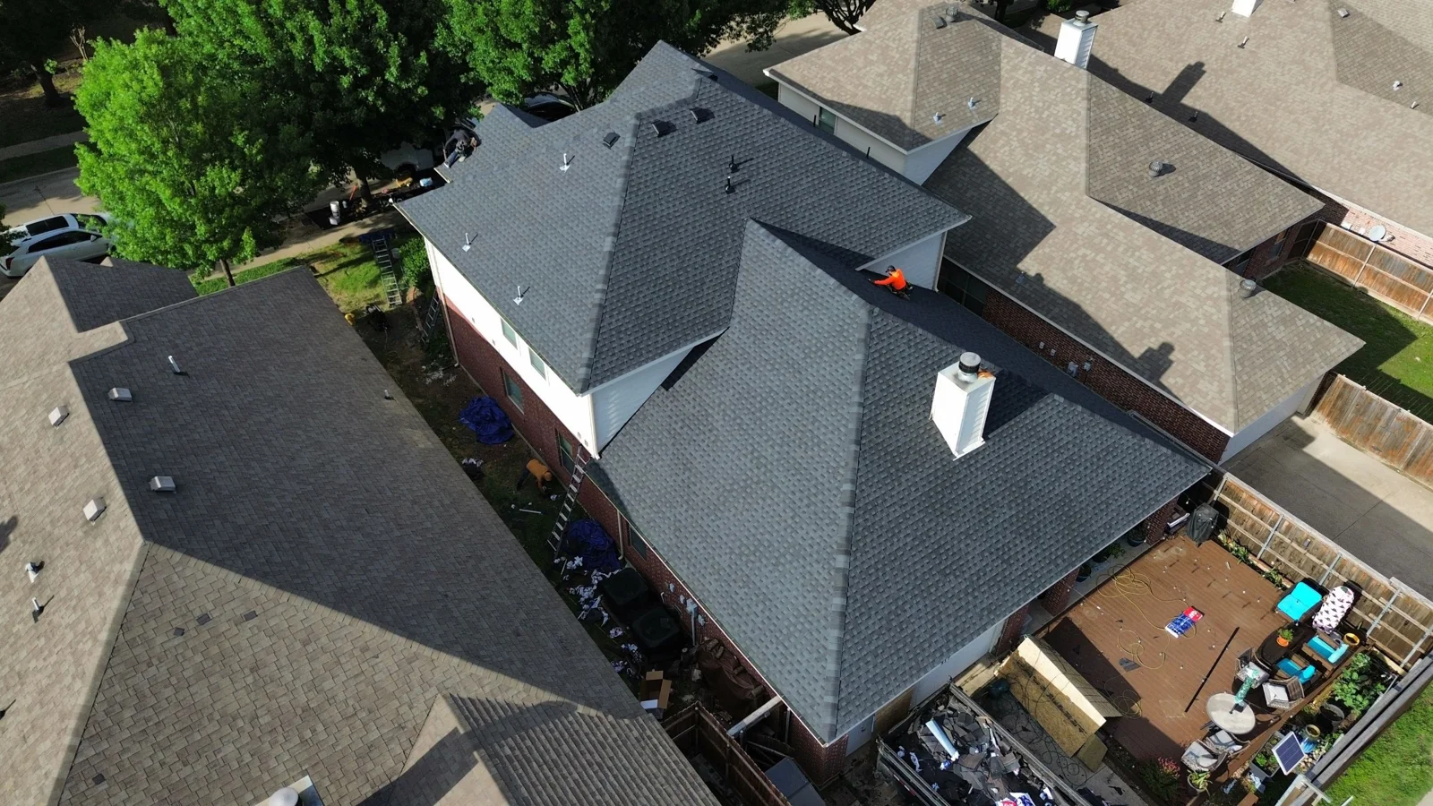 Aerial view of newly installed gray shingles on a Red Oak home, with crew still on site